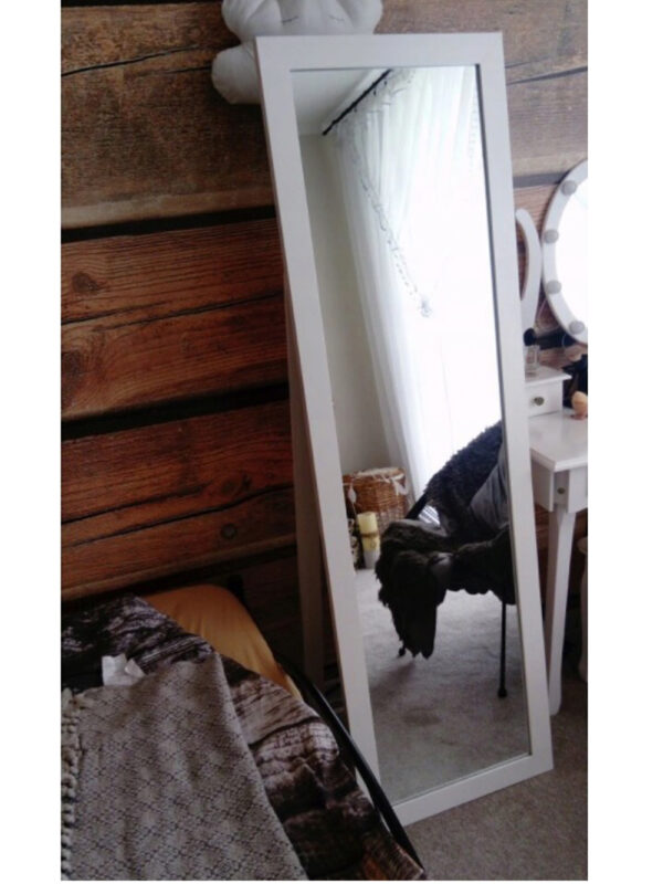 lustro w białej ramie stojące oprawione w sypialni z nóżką